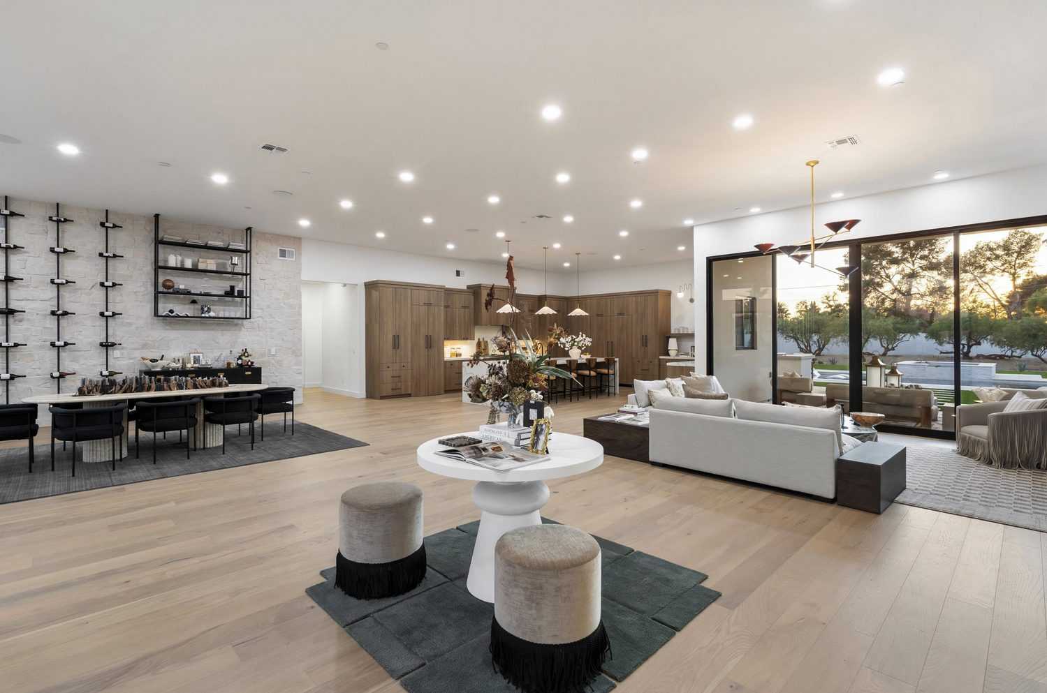 Open great room with dining, kitchen and living areas and a glass wall to the yard